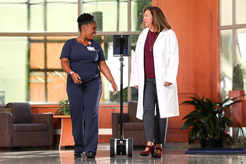 A nurse and a doctor having a teleconfrence while walking down a hallway 